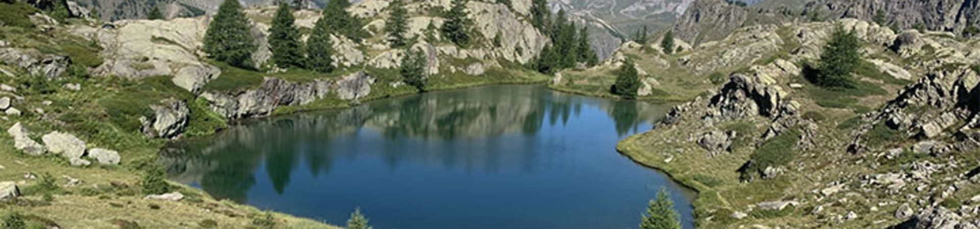 Lac alpin entouré de rochers et de mélèzes - Grande Traversée des Alpes - France