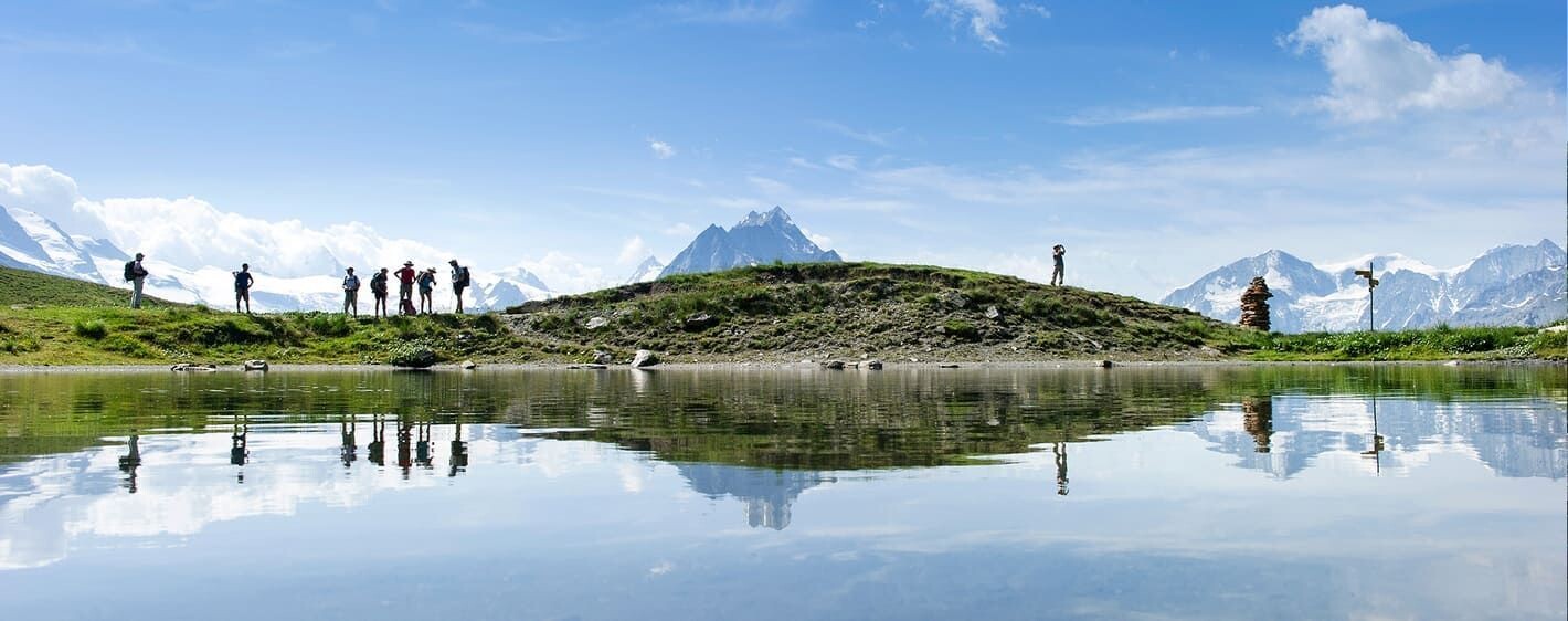 Randonneurs et reflets dans un lac alpin - Tour du Cervin - Alpes - Suisse