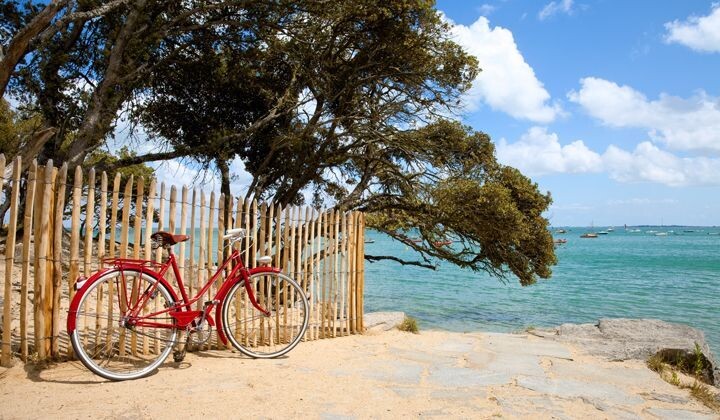 Vélo rouge contre une barrière de bois sur la plage - Île de Noirmoutier - Vendée