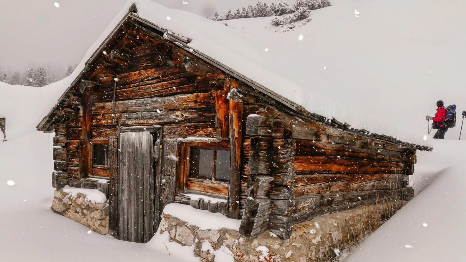 © Anne Moraw Chalet de bois sous la neige et randonneur - Dolomites - Italie