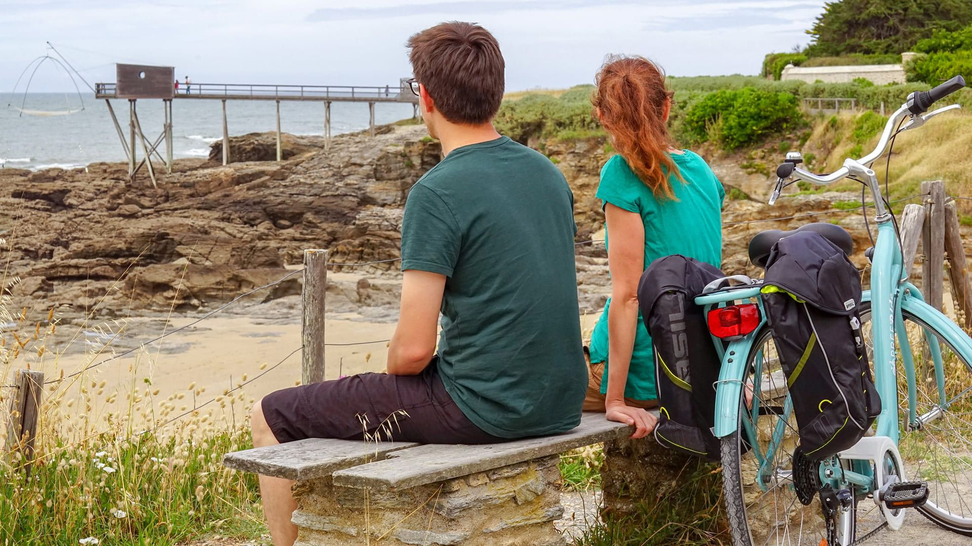 © Aurélie Stapf Cyclistes sur un banc face à la mer et à un carrelet - Côte de Jade - France