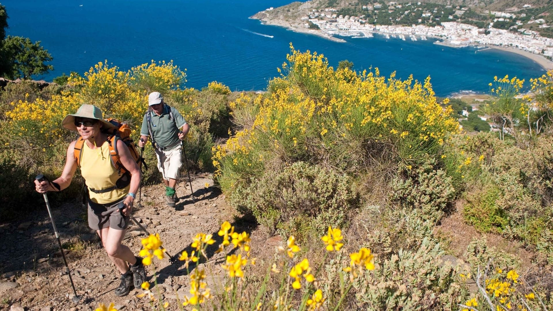 Randonneurs sur un sentier côtier fleuri au-dessus du port - Costa Brava - Espagne