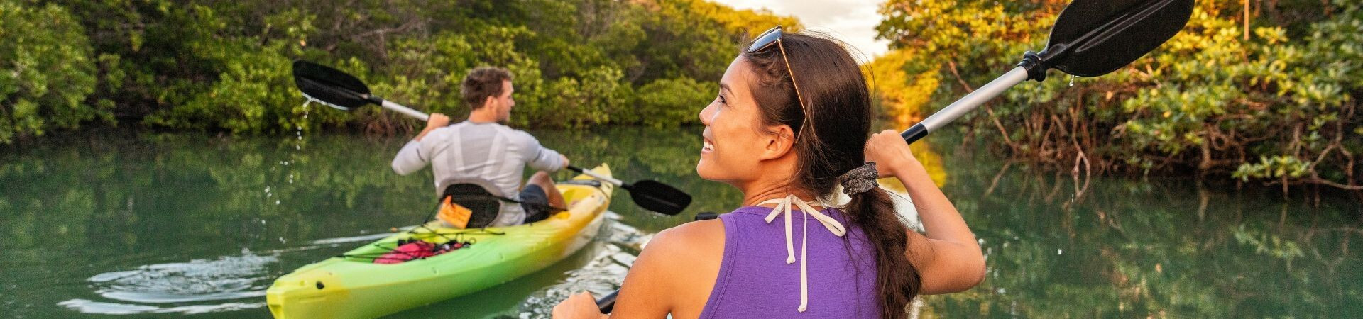 Couple en kayak sur une rivière tropicale bordée de mangroves