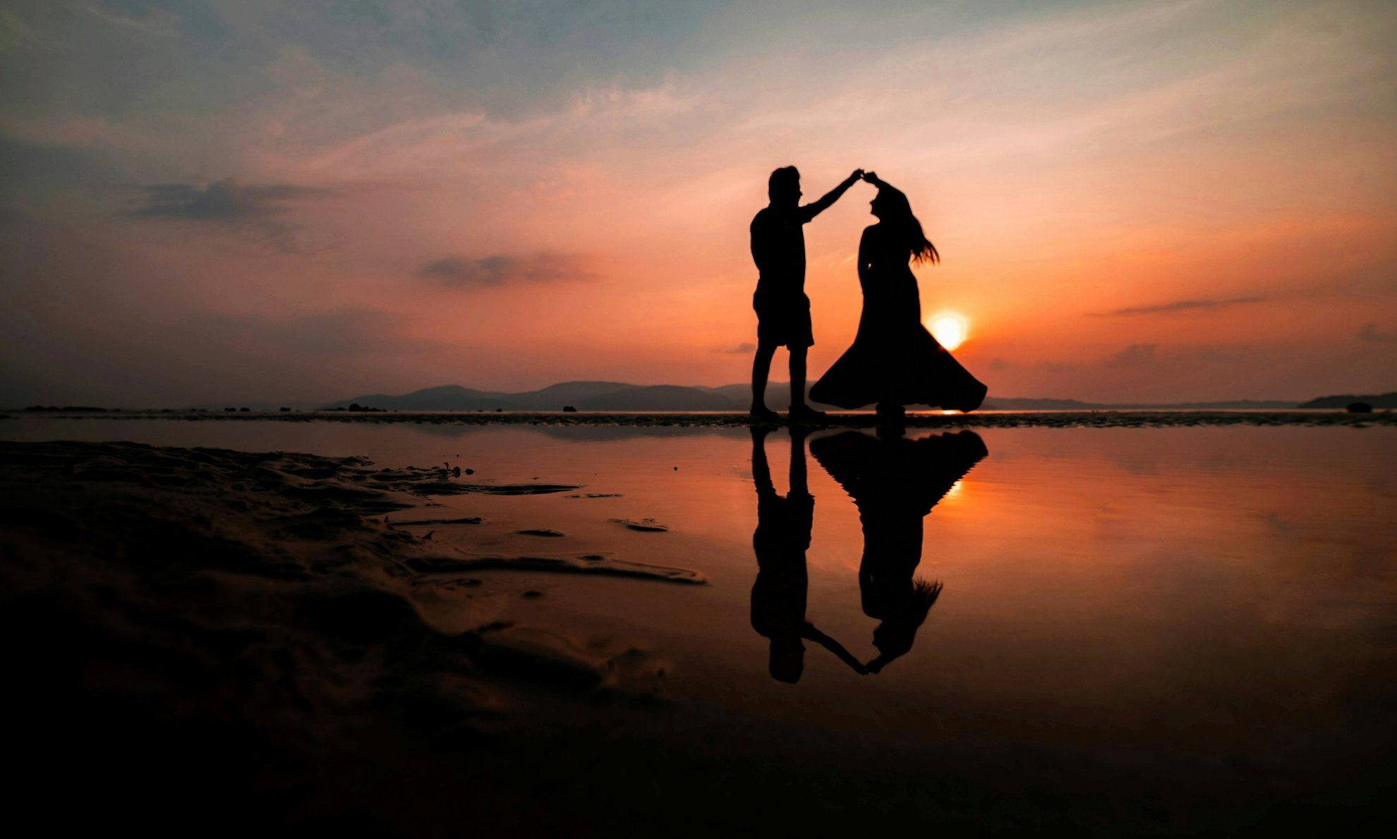 Couple dansant en silhouette au coucher de soleil sur la plage