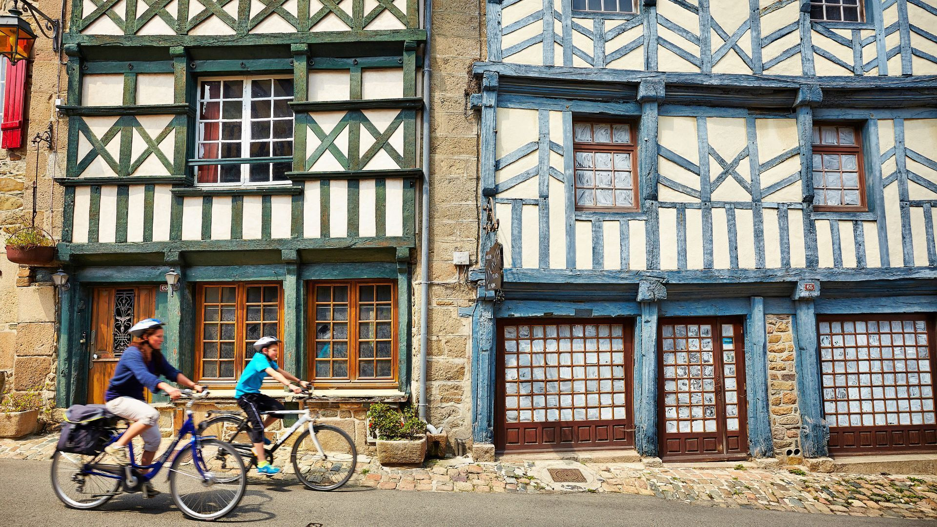 Cyclistes devant des maisons à colombages - Bretagne - France
