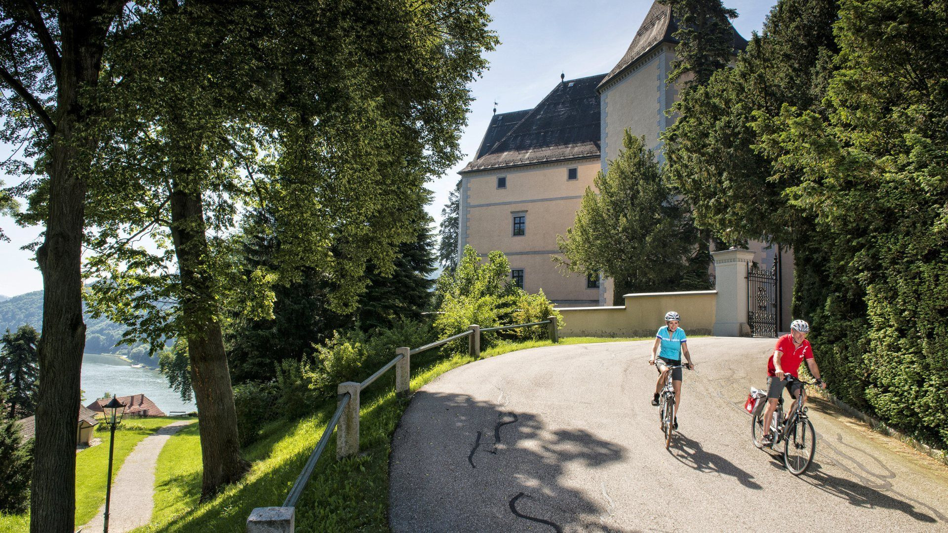 Cyclistes devant un château au bord du lac - Autriche