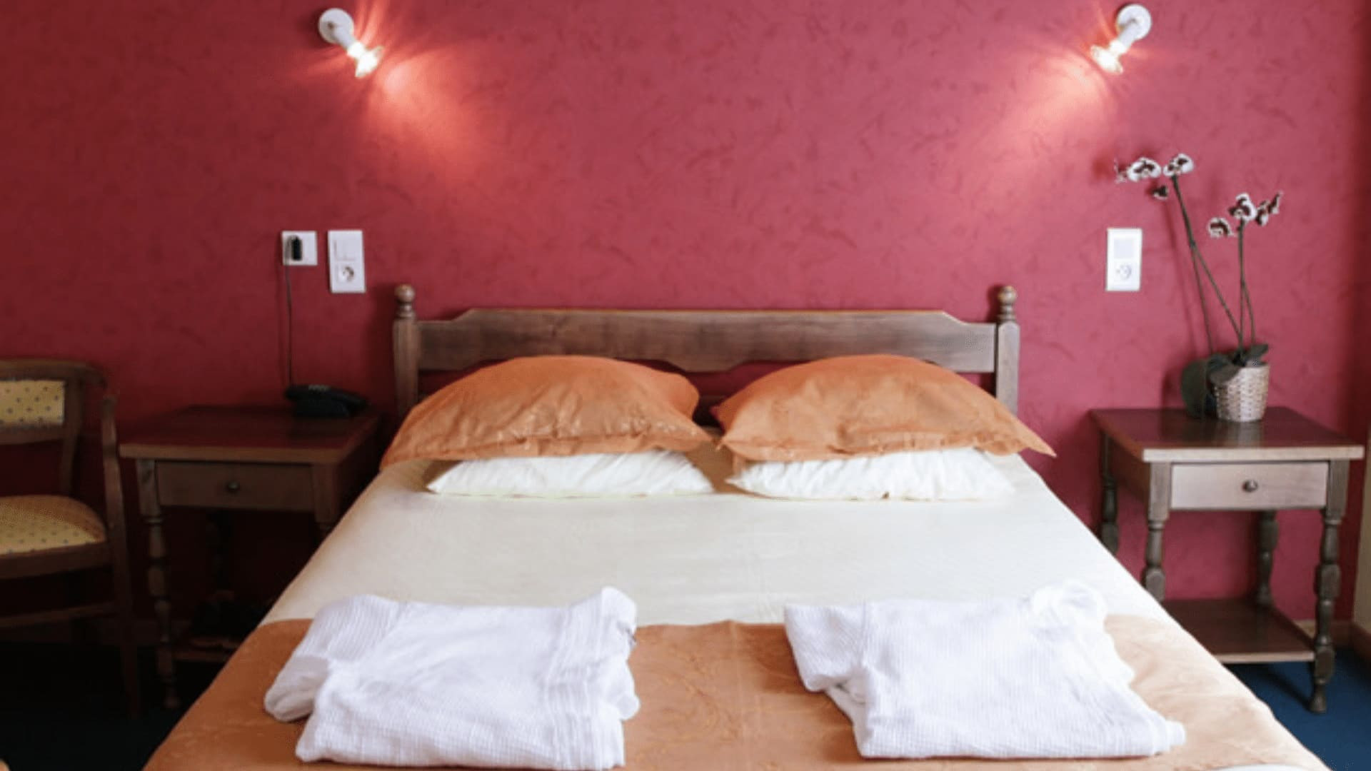 Chambre d'hôtel aux murs framboise et coussins orange - France