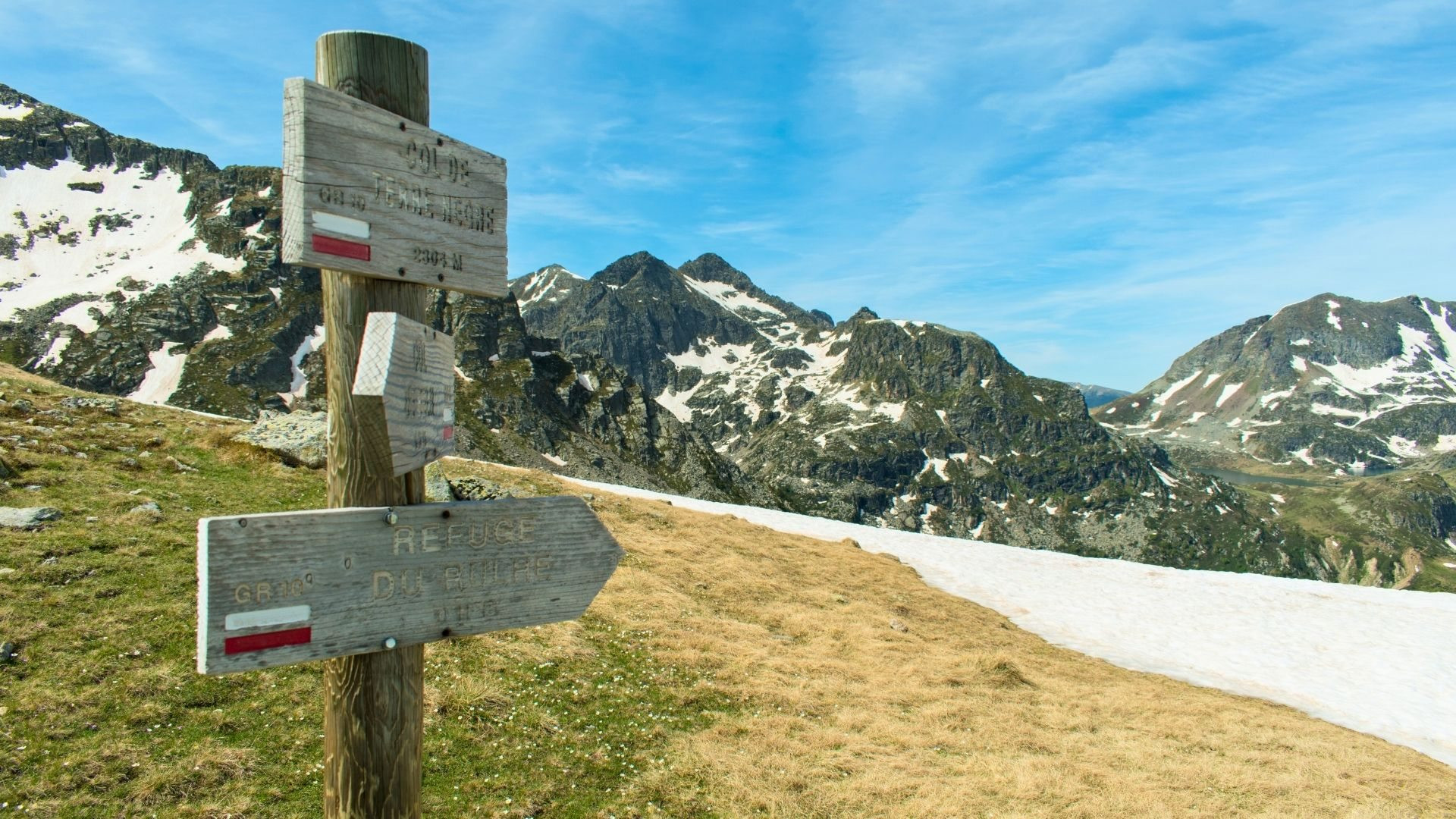 Poteau indicateur balisé GR face aux sommets enneigés des Pyrénées