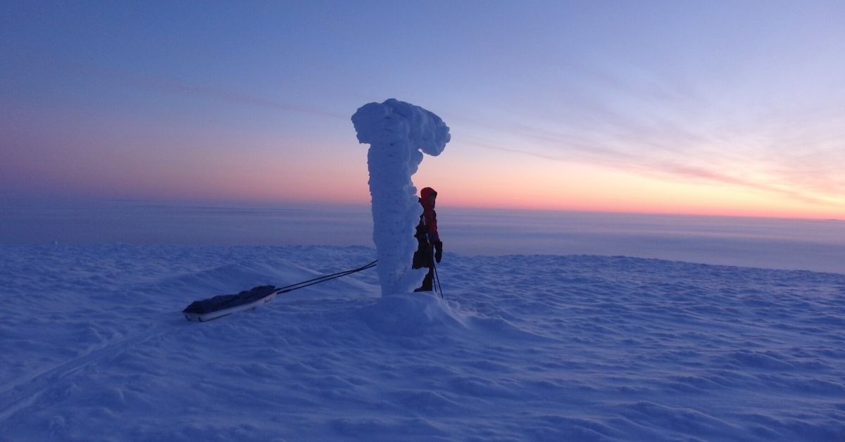 Randonneur tractant une pulka au crépuscule polaire - expédition hivernale