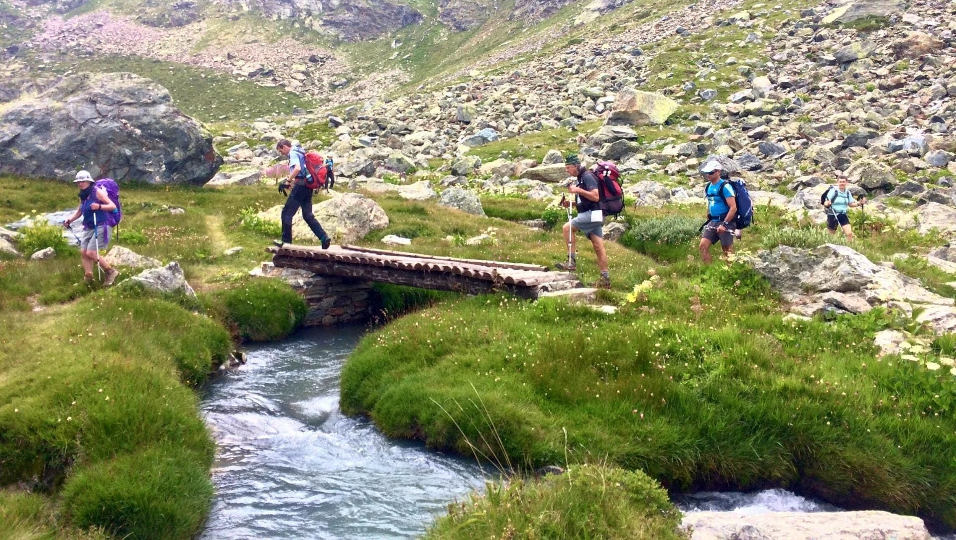 Randonneurs traversant un pont de bois sur un torrent - Tour des Géants - Val d'Aoste, Italie