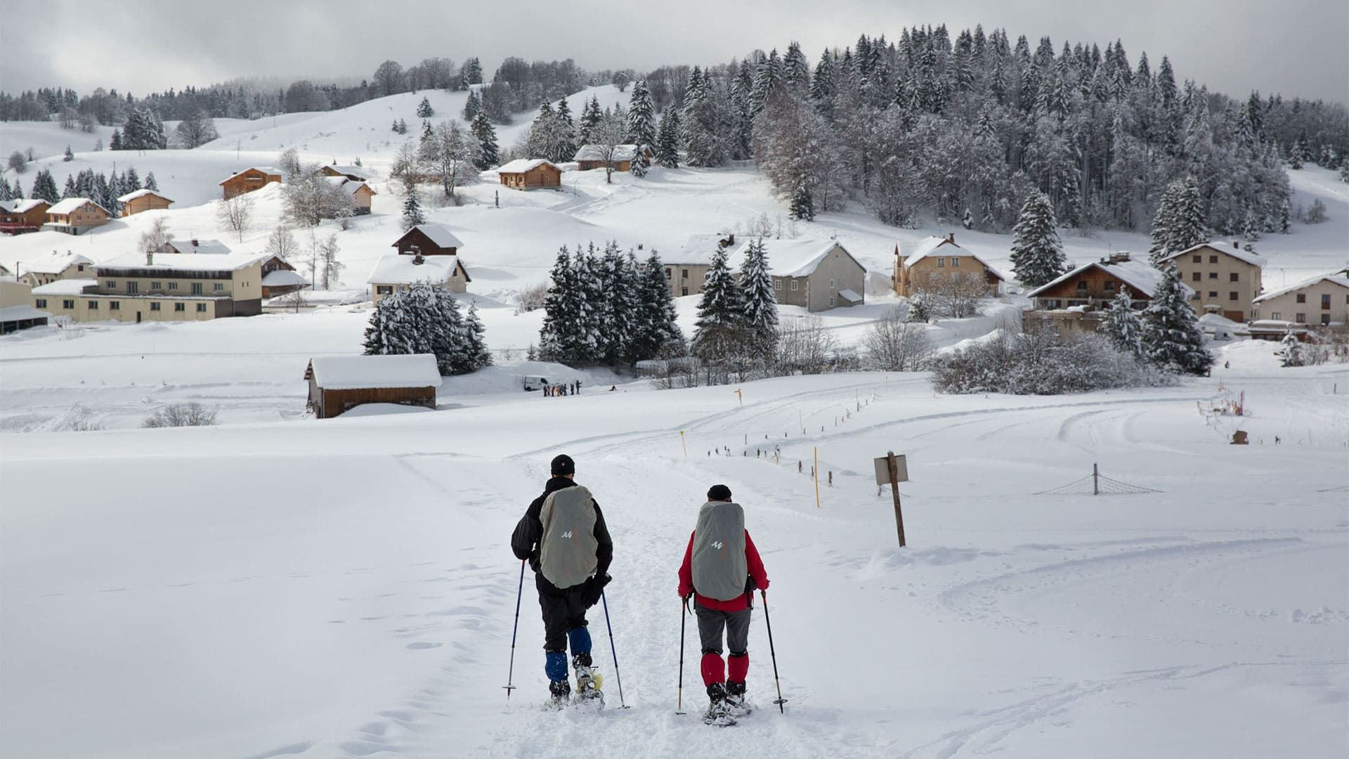 © Lex Van Den Bosch Randonneurs en raquettes au-dessus d'un village - Grande Traversée du Jura - France