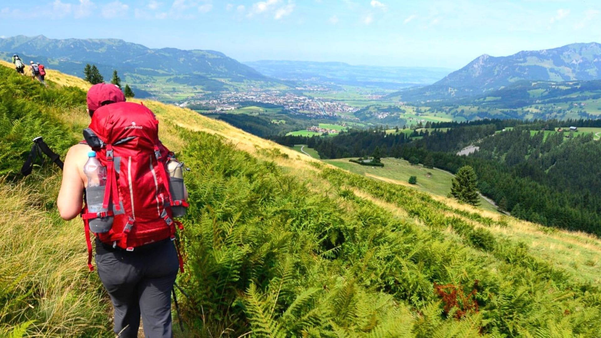 © Jean-Marc Porté Randonneuse sur crête verdoyante avec vue sur la vallée - Alpes bavaroises
