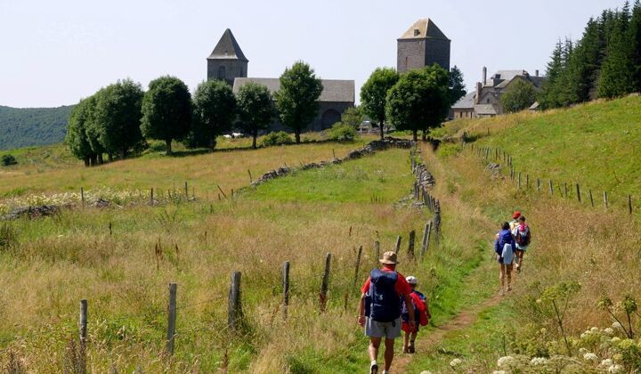 Randonneurs vers le village et son église - Aubrac - Chemin de Saint-Jacques, France