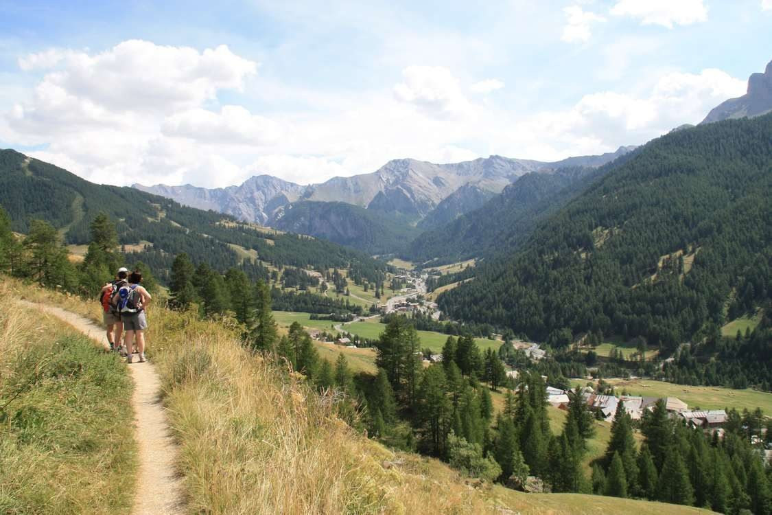 © Marc Laurans Randonneurs dominant une vallée et un village de montagne - Queyras - Alpes, France