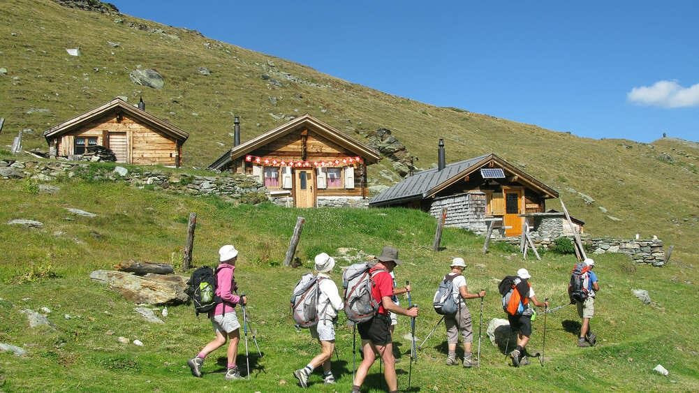 Randonneurs passant devant des chalets d'alpage - Valais - Suisse