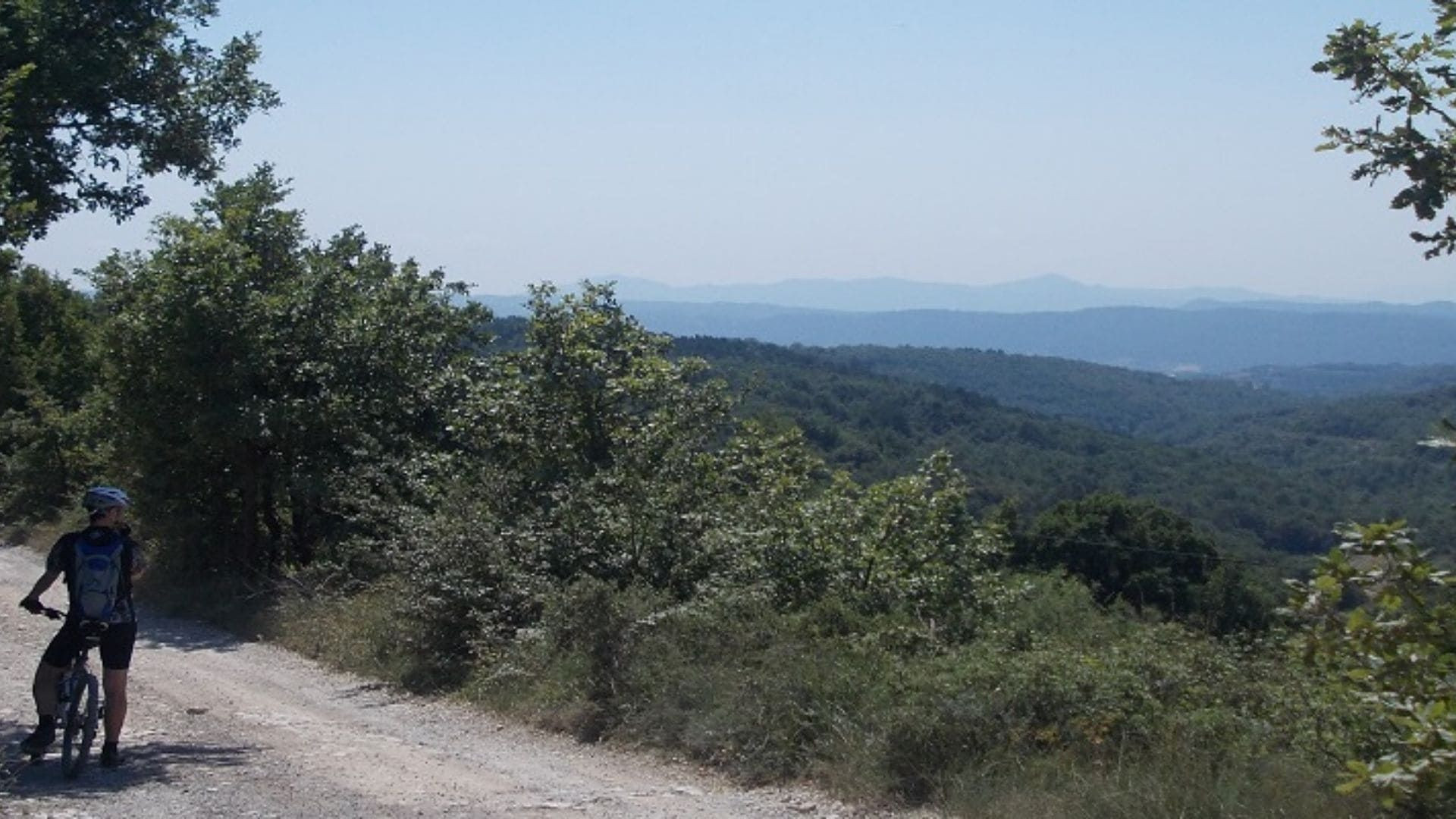 Cycliste sur une piste face aux collines boisées - Catalogne - Espagne