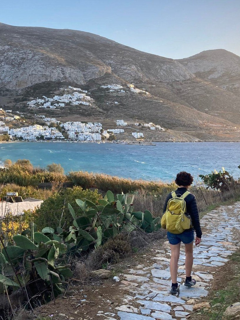 © Wilfrid Valette Randonneuse sur un chemin pavé au-dessus de la baie d'Amorgos dans les Cyclades