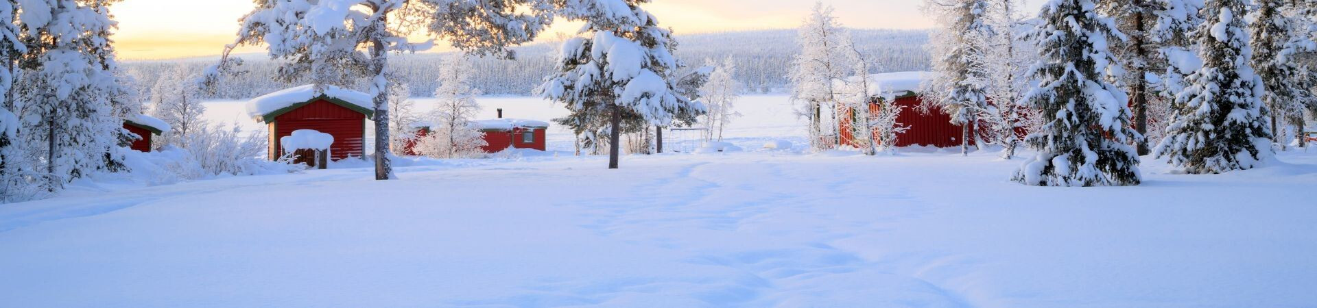 Chalets rouges et sapins enneigés au coucher de soleil - Laponie scandinave