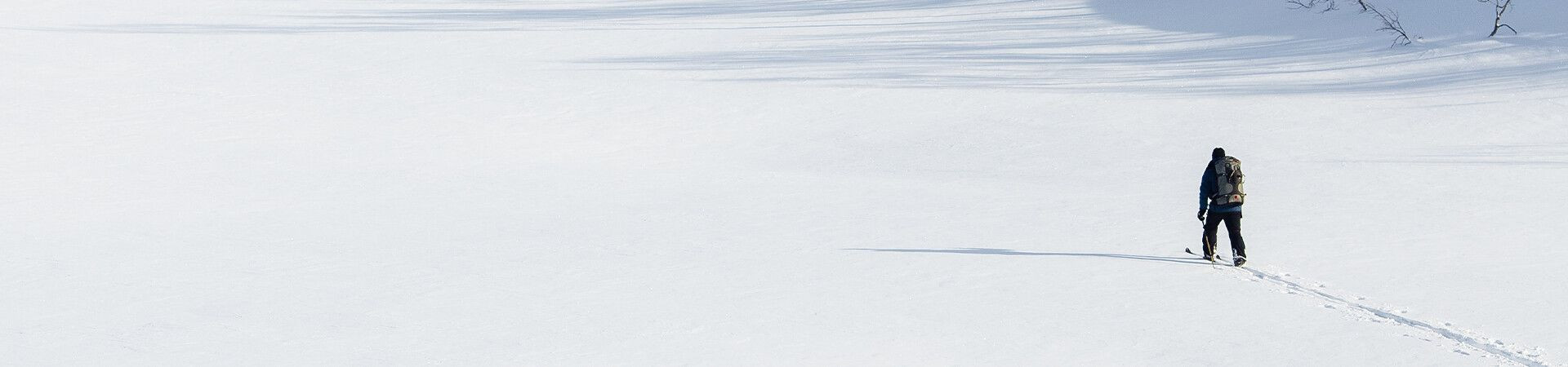 Skieur solitaire traversant une vaste plaine enneigée - Ski nordique