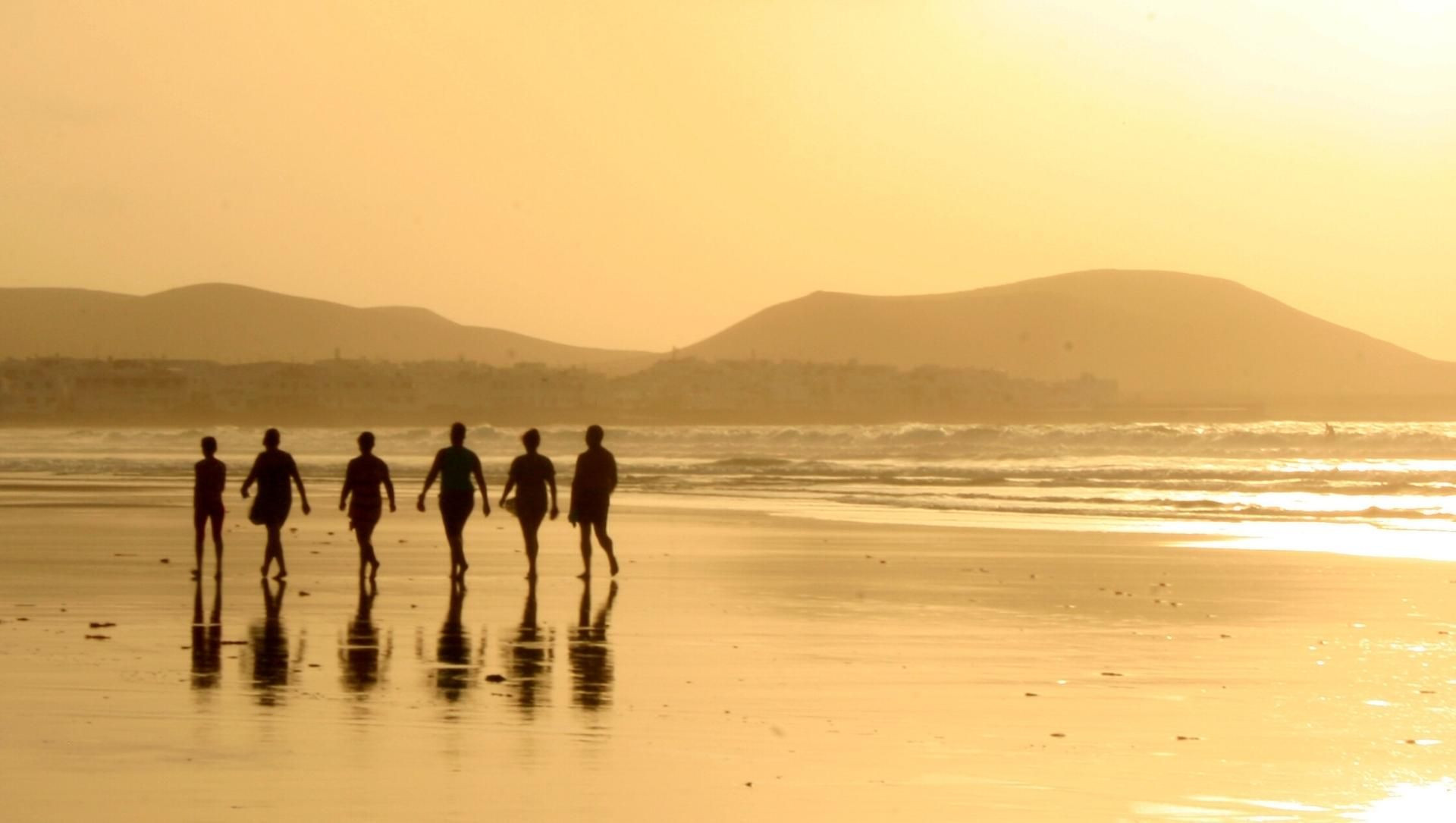 © Turismo De Canarias Promeneurs sur une plage au coucher du soleil à Lanzarote - Canaries - Espagne