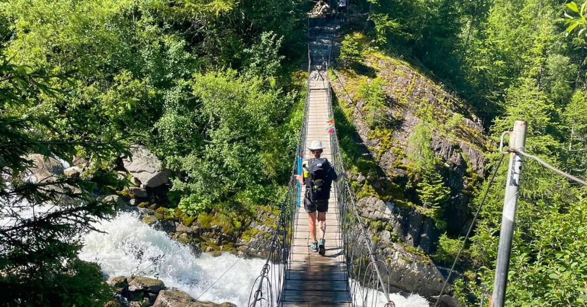 Randonneur sur une passerelle au-dessus d'un torrent - Tour du Mont-Blanc - Haute-Savoie, France