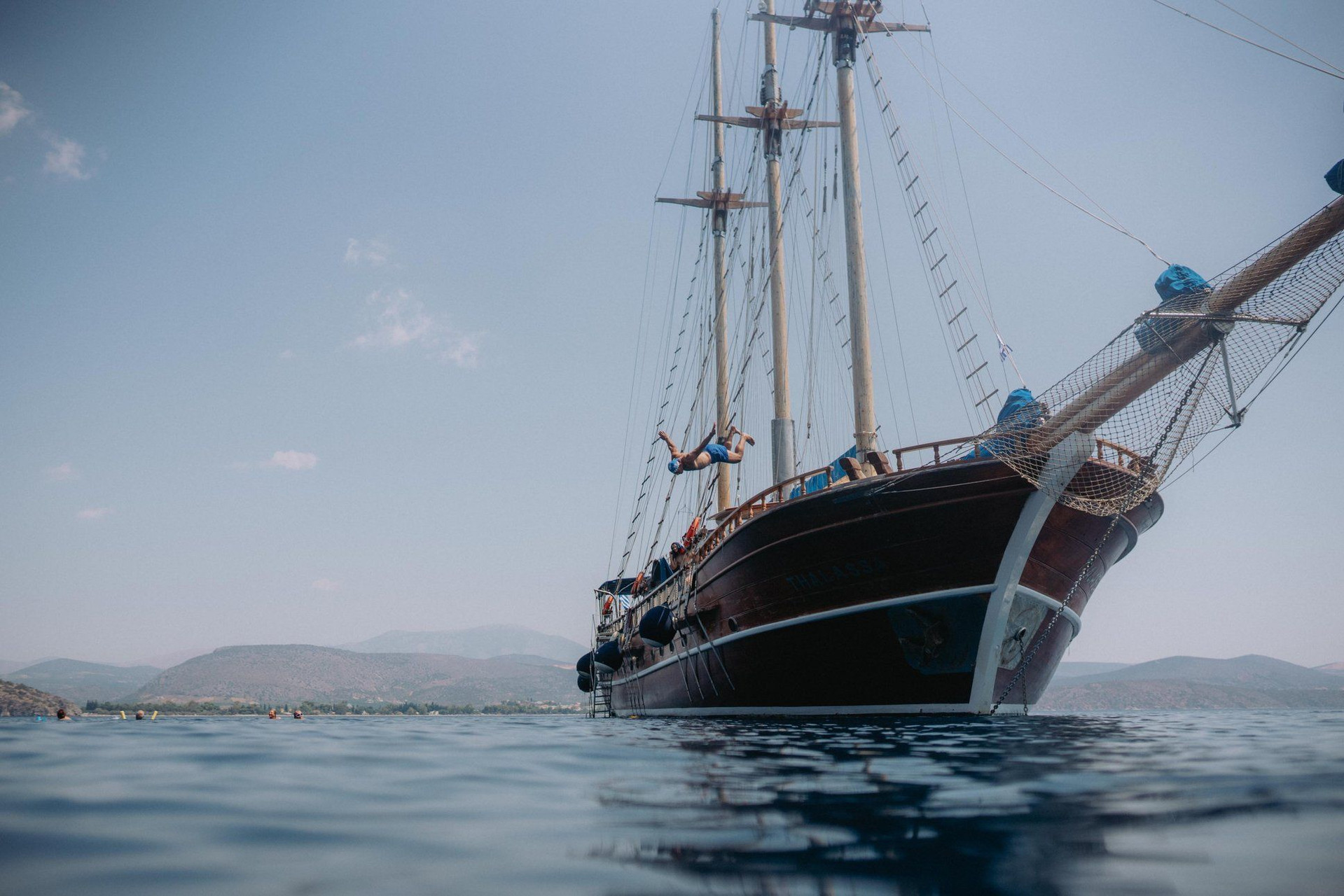 © Kleomenis Koufaliotis Goélette traditionnelle au mouillage et baigneurs - mer Égée - Grèce