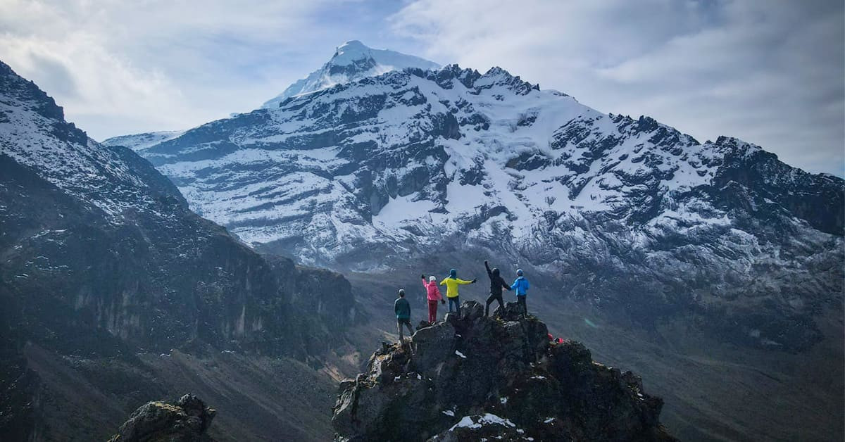 Trekkeurs au sommet face au volcan enneigé - Équateur