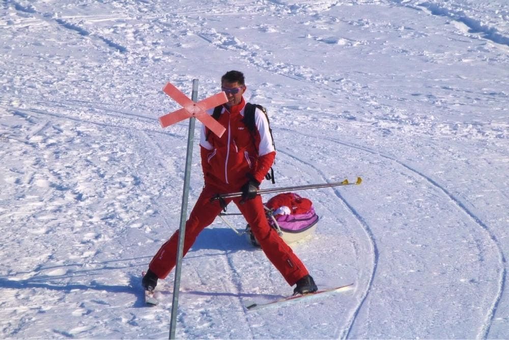 Skieur devant une croix rouge de ralliement sur la Kungsleden en Suède